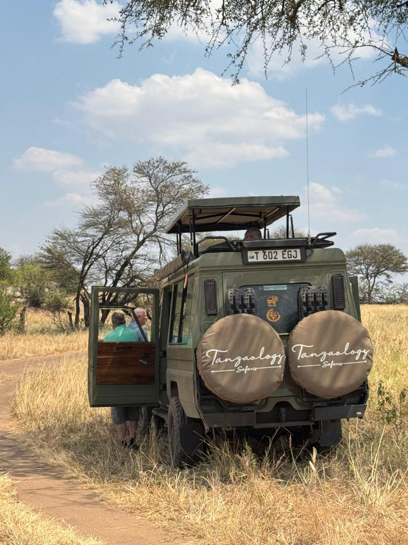Two Tanzaology safari vehicles parked side by side