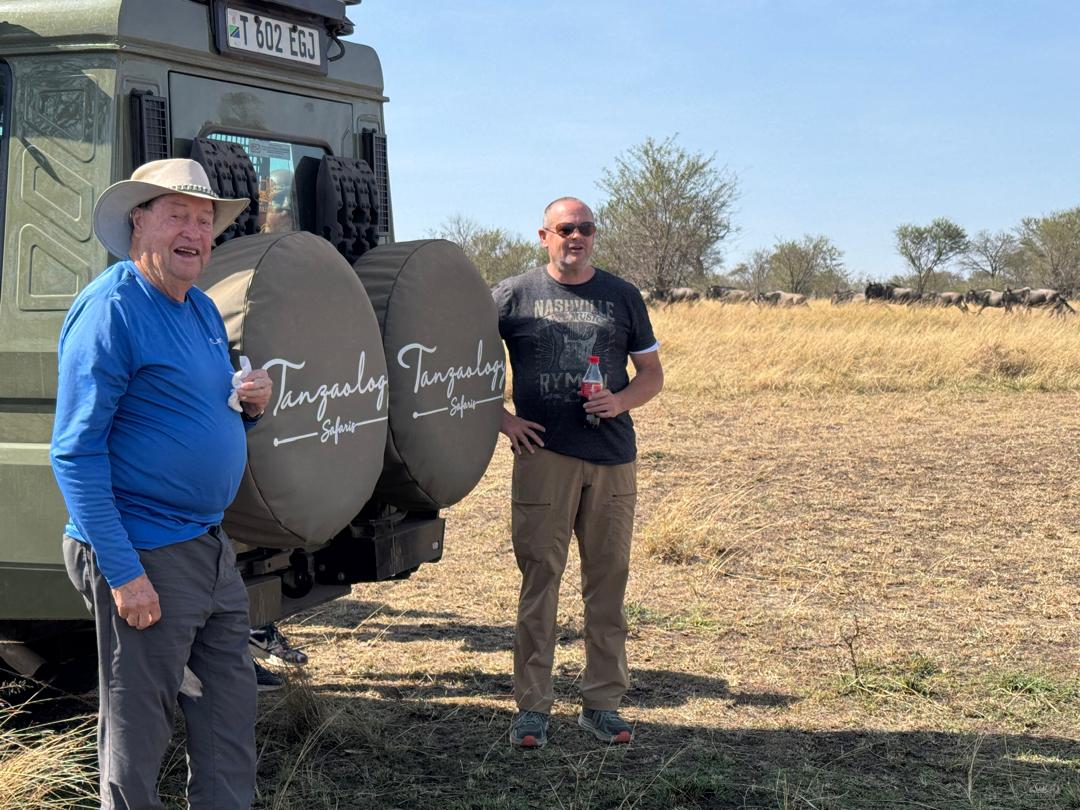 Two guests standing beside a Tanzaology Land Cruiser